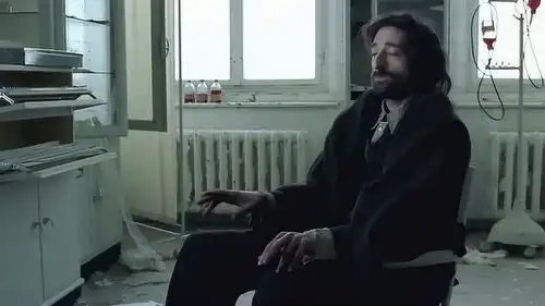 钢琴家席皮尔曼坐在板凳上,听着别人弹奏的钢琴师手不自觉的挥舞
