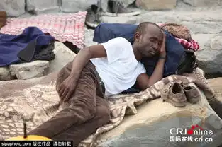 意法边境的非洲移民蜗居海边岩石等待
